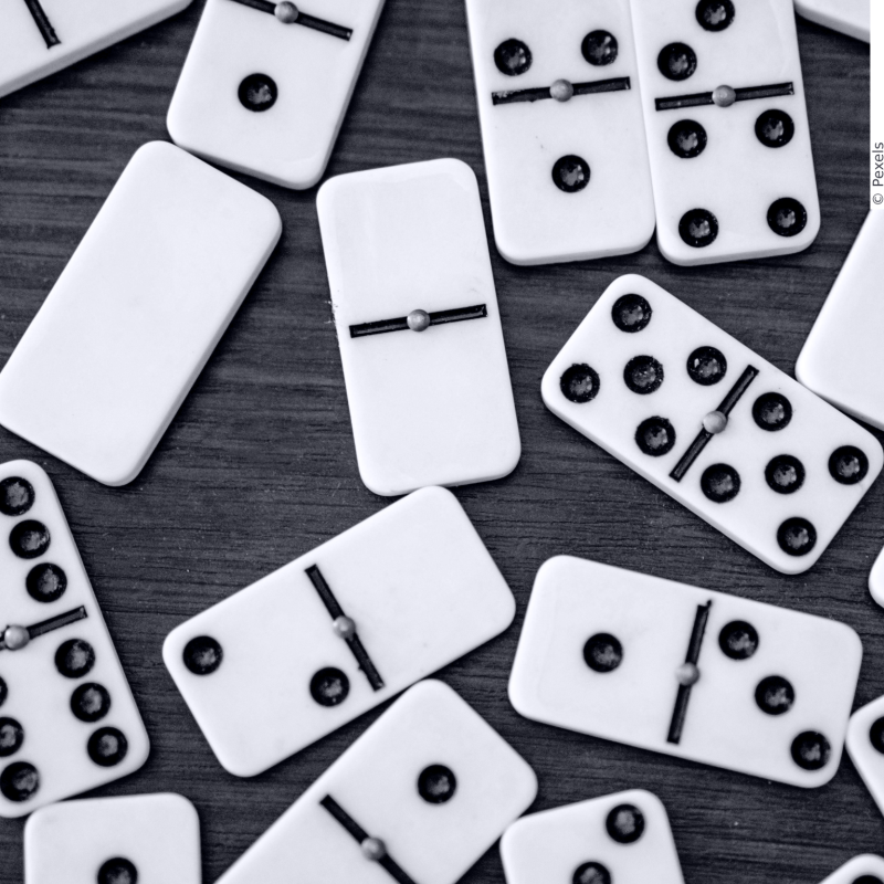 In this picture you can see dominoes lying on a wooden table.