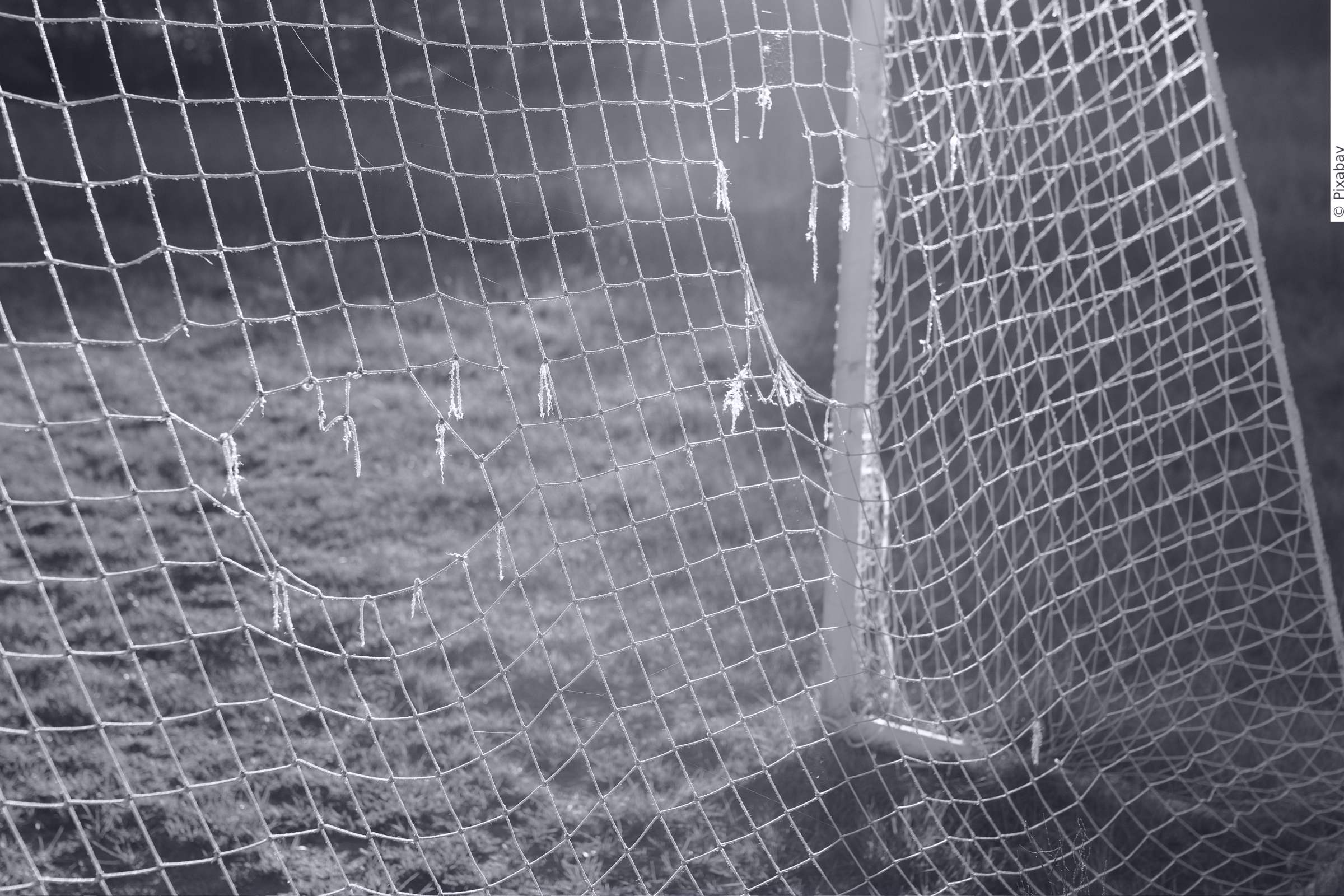A goalpost in an outdoors playing field with holes in it.