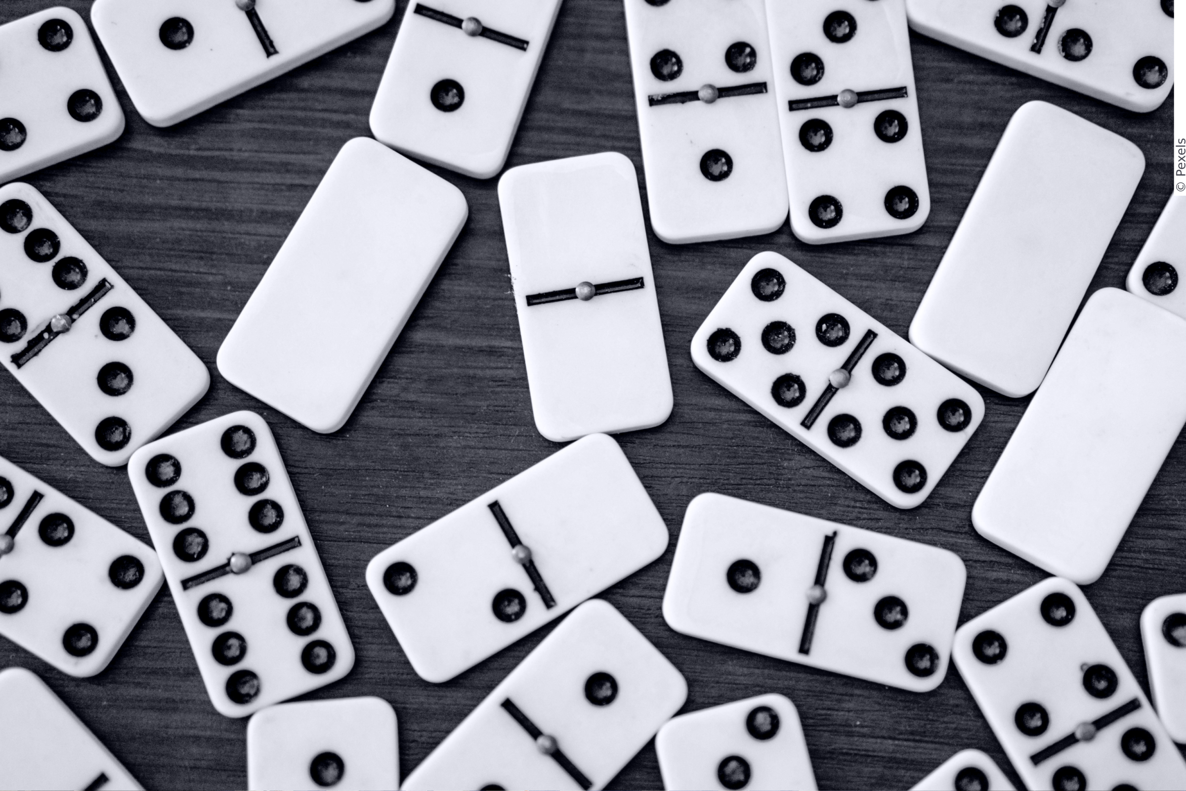 In this picture you can see dominoes lying on a wooden table.