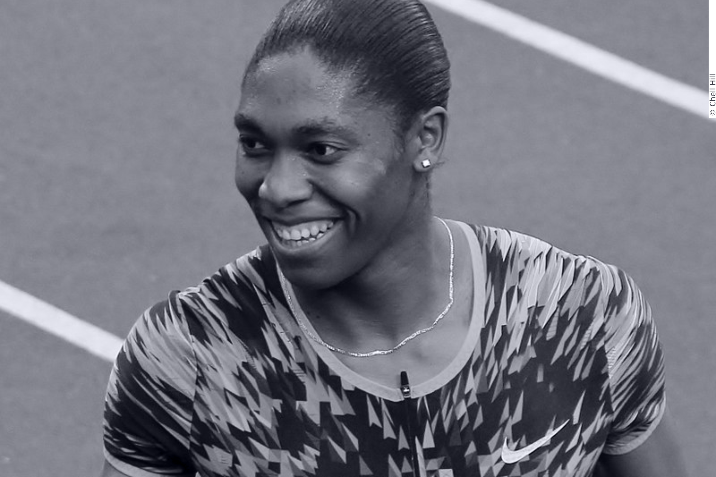 In this picture Caster Semenya is portrayed. She is smiling and is wearing i a patterned shirt.